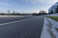 an empty street next to grassy area on which to the road is marked and it has white marking in white