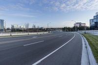 an empty street next to grassy area on which to the road is marked and it has white marking in white