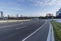 an empty street next to grassy area on which to the road is marked and it has white marking in white