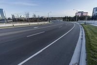 an empty street next to grassy area on which to the road is marked and it has white marking in white