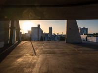 an empty empty street is seen during sunset with the sun setting over it and a city in the distance