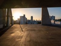 an empty empty street is seen during sunset with the sun setting over it and a city in the distance