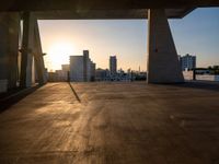 an empty empty street is seen during sunset with the sun setting over it and a city in the distance