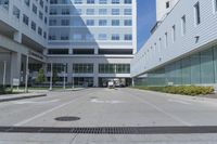 there is an empty street outside of an office building, as well as a large building with many windows