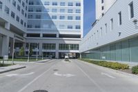 there is an empty street outside of an office building, as well as a large building with many windows