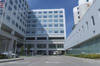 there is an empty street outside of an office building, as well as a large building with many windows