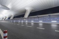 this is an empty street in the middle of an airport building with curved pillars on top