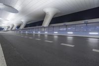 this is an empty street in the middle of an airport building with curved pillars on top