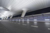 this is an empty street in the middle of an airport building with curved pillars on top