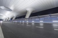 this is an empty street in the middle of an airport building with curved pillars on top