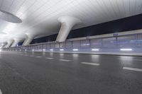 this is an empty street in the middle of an airport building with curved pillars on top