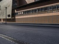 the side view of an empty street near a brick building with many windows on it