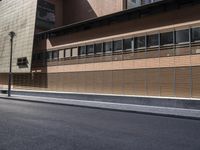 the side view of an empty street near a brick building with many windows on it