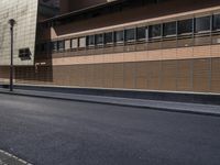 the side view of an empty street near a brick building with many windows on it