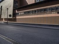 the side view of an empty street near a brick building with many windows on it