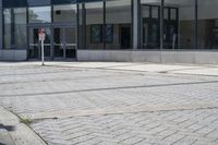 a person sitting at the bench in front of a mall that is empty of people