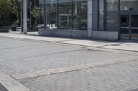 a person sitting at the bench in front of a mall that is empty of people