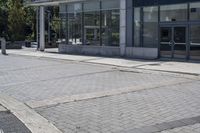 a person sitting at the bench in front of a mall that is empty of people