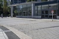 a person sitting at the bench in front of a mall that is empty of people