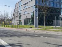 an empty street near a large modern glass building and a man with a bike on a city street