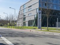 an empty street near a large modern glass building and a man with a bike on a city street