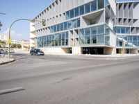 an empty street with no cars outside of a building and two black cars on the road