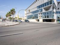 an empty street with no cars outside of a building and two black cars on the road