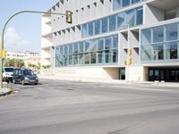 an empty street with no cars outside of a building and two black cars on the road