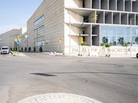 an empty street with no cars outside of a building and two black cars on the road