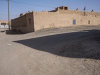 an empty street near a wall with a building on it in the background and a small patch of dirt around