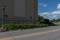 the street is empty as a motorcycle rides past it on the road behind the building