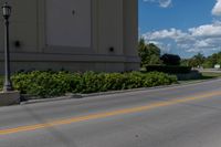 the street is empty as a motorcycle rides past it on the road behind the building