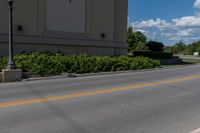 the street is empty as a motorcycle rides past it on the road behind the building