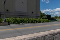 the street is empty as a motorcycle rides past it on the road behind the building