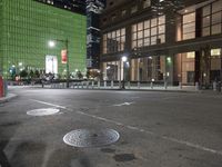 an empty street in front of tall buildings on a busy city street at night time