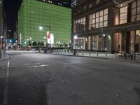 an empty street in front of tall buildings on a busy city street at night time
