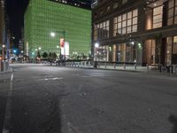 an empty street in front of tall buildings on a busy city street at night time