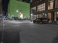 an empty street in front of tall buildings on a busy city street at night time