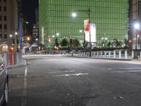 an empty street in front of tall buildings on a busy city street at night time