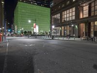 an empty street in front of tall buildings on a busy city street at night time