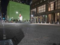 an empty street in front of tall buildings on a busy city street at night time