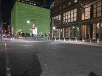 an empty street in front of tall buildings on a busy city street at night time