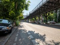 an empty street next to a bridge in a city with some people walking on the road