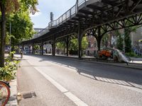 an empty street next to a bridge in a city with some people walking on the road