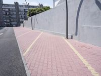 the sidewalk of an empty street next to a wall of tall buildings and parking spaces