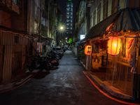 a night shot showing a street that is empty with motorcycle parked in it and a building in the background