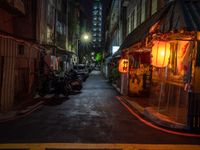 a night shot showing a street that is empty with motorcycle parked in it and a building in the background