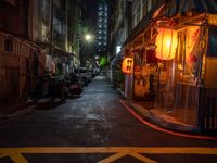 a night shot showing a street that is empty with motorcycle parked in it and a building in the background