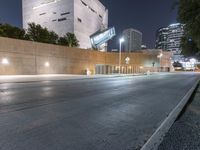 an empty street with no cars on it at night, in front of skyscrapers