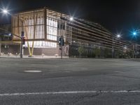 an empty street is lit up at night, including traffic light, sidewalk and building